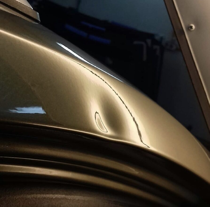 Hageldelle im Reflexionsstreifen einer Motorhaube